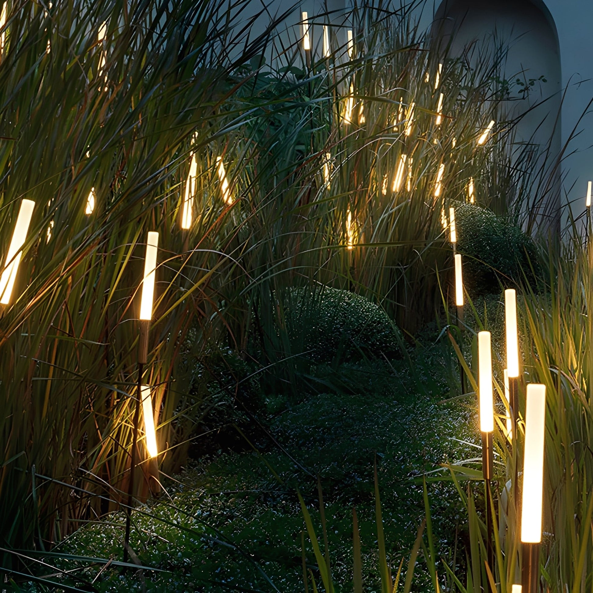 Tuinlamp met rietlook kap geplaatst tussen planten in de tuin