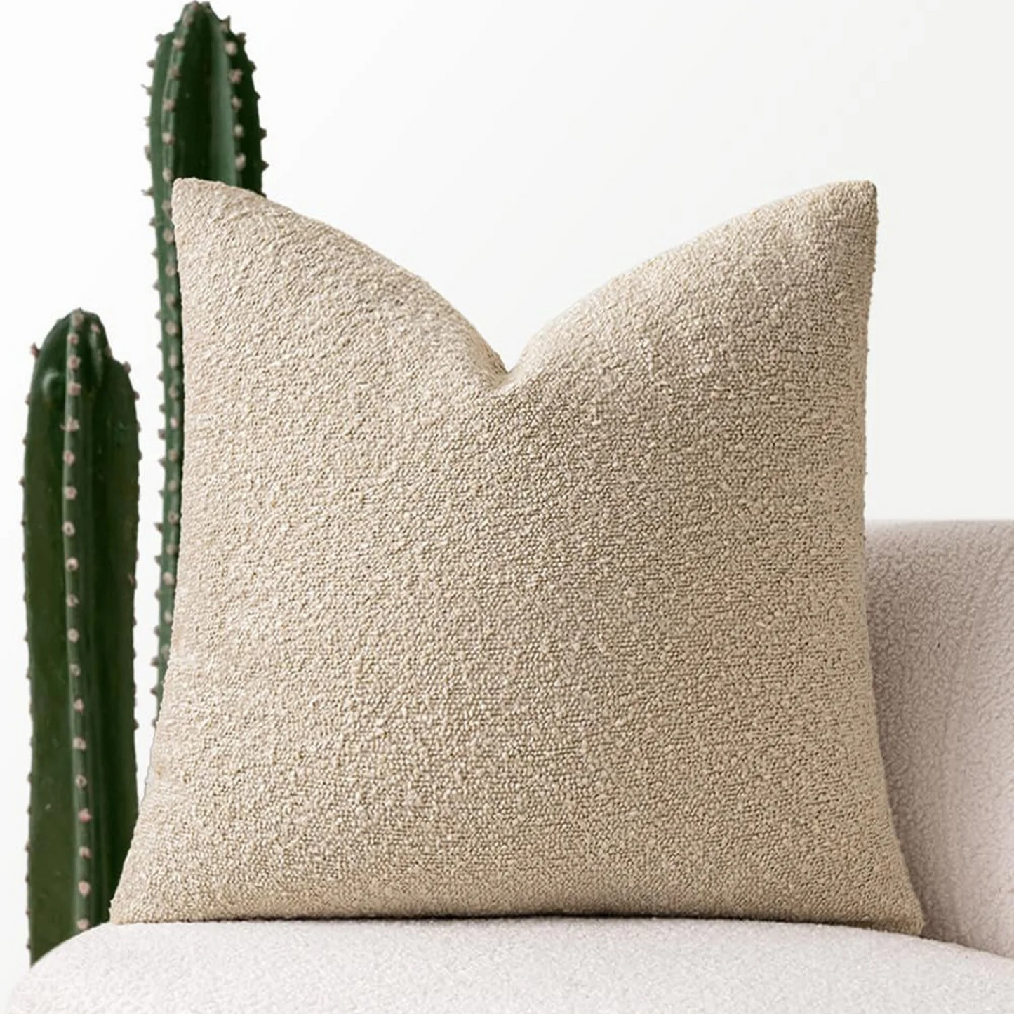 sierkussenhoes van bouclé polyester gecombineerd met andere kussens op bed