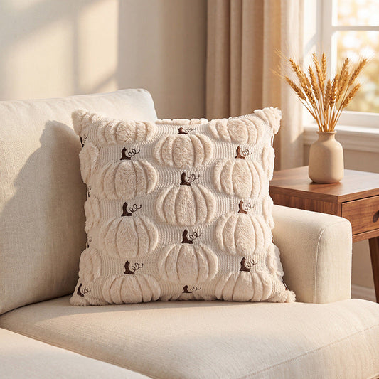 Pluchen sierkussen met pompoenmotief, decoratief geplaatst in een sfeervol interieur.