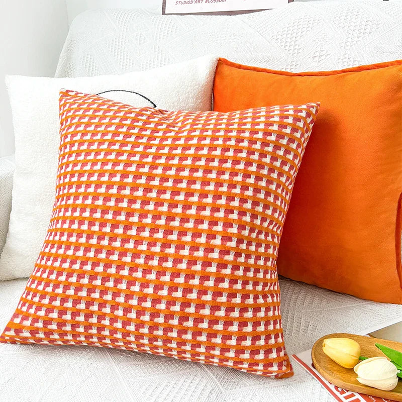 Geometrische contrastkleurige kussenhoes gestyled op een stoel