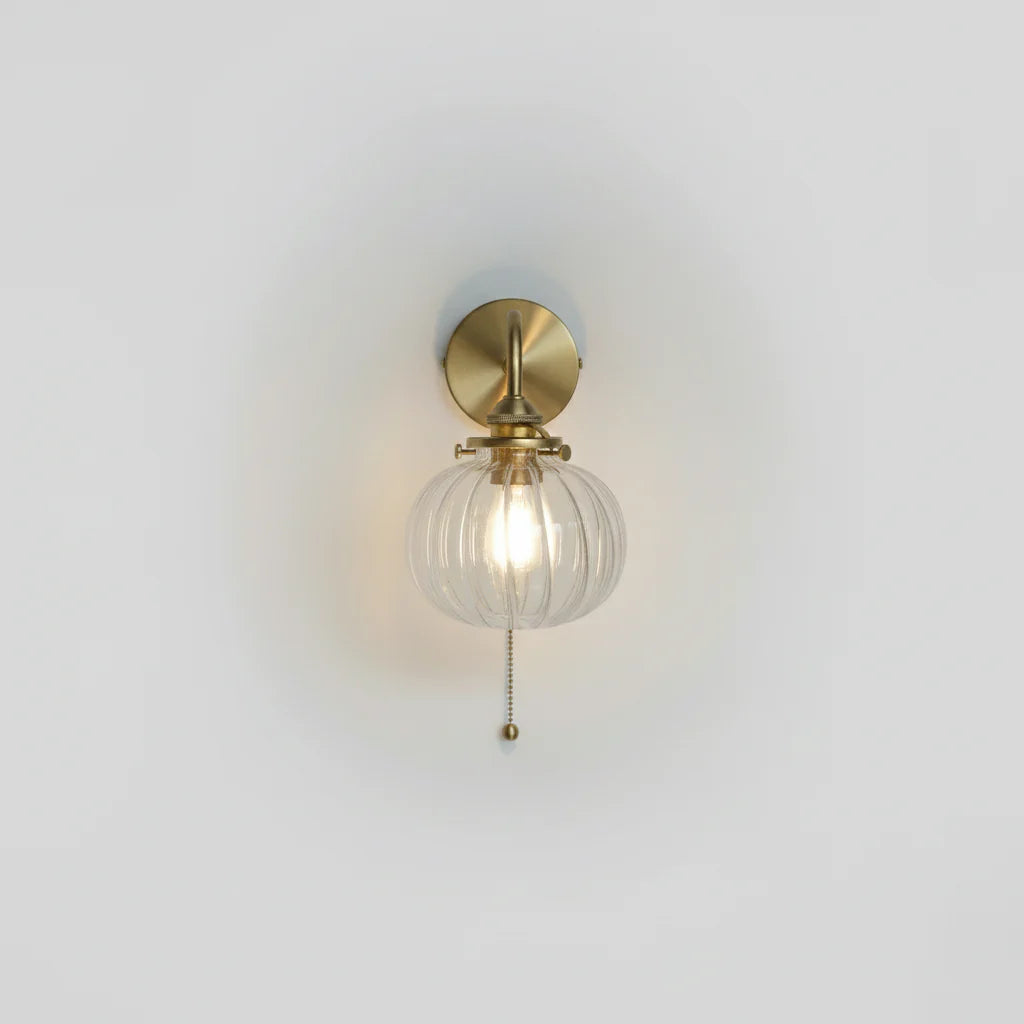 wandlamp met trekkoord in goudkleurig metaal en bolvormige glazen kap
